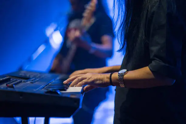Photo of Pianist playing electric piano in concert at night, music concept.