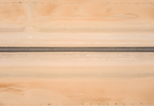 Straight railroad track passing through a sandy desert.