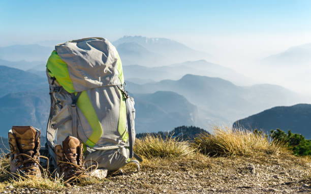 Hiking equipment. Backpack and boots on top of mountain. Hiking equipment. Backpack and boots on top of the mountain. Beautiful view to mountain ranges and fog filled valleys. backpack stock pictures, royalty-free photos & images