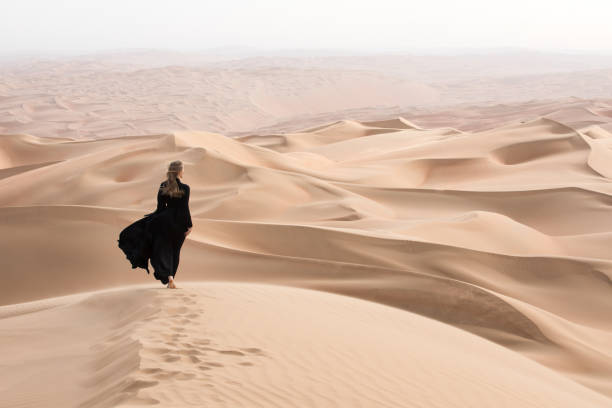 junge frau in abaya posiert in wüstenlandschaft. - liwa desert stock-fotos und bilder