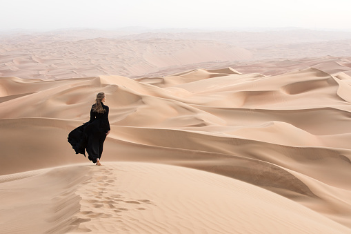 Mujer joven en Abaya posando en el desierto. photo