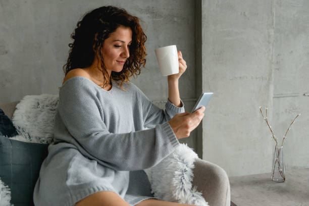 istock Young woman with mobile phone and coffee 925385338