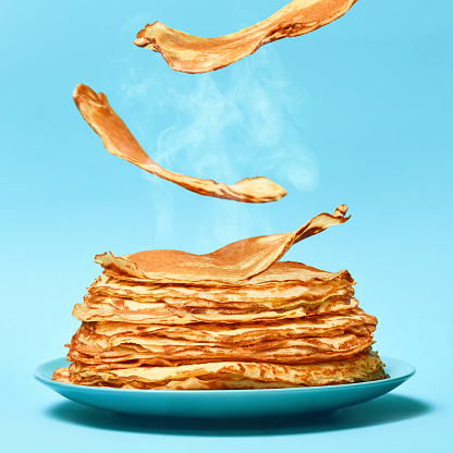 French pancakes is flying on the blue background. Pancakes in blue plate. Food concept.