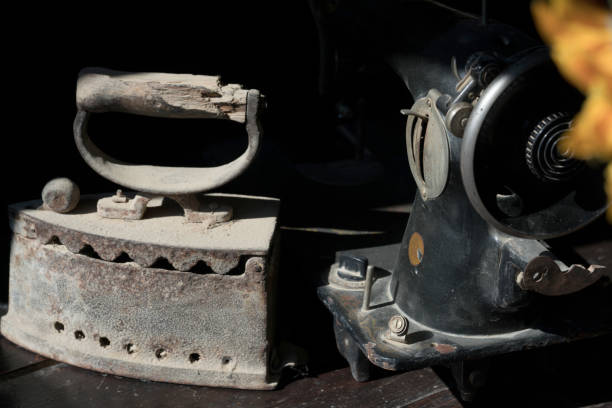 istock Old abandoned sewing machine and iron on a black background 925392060
