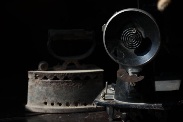 istock Old abandoned sewing machine and iron on a black background 925392416