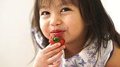 Little Asian baby girl is eating strawberry at her room