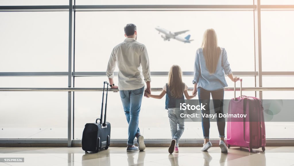 Family in airport Family in airport. Attractive young woman, handsome man and their cute little daughter are ready for traveling! Happy family concept. Airport Stock Photo
