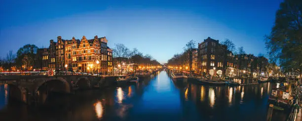 Amsterdam tranquil canal scene with canal houses, bicycles and bridge in the Jordaan neighborhood by night in Netherlands. Shot in long exposure on blue hours.