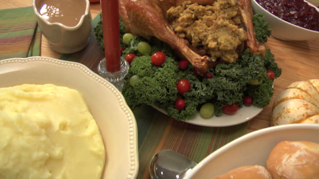 Camera pans over dinner table with turkey and other Thanksgiving dishes