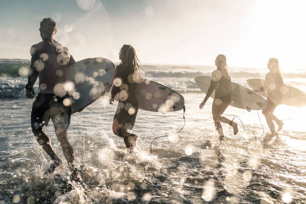 Friends running into the sea with surfboards.