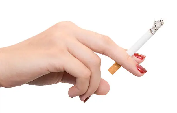 Photo of Woman's hand with red nail polish holding a cigarette