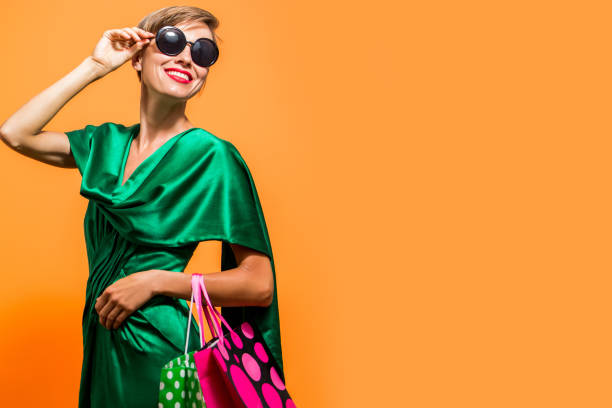 Young happy summer shopping woman with shopping bags isolated over bright orange background