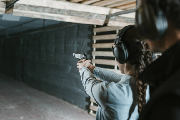 vista trasera del chica disparando con la pistola en la galería de tiro - target shooting fotografías e imágenes de stock