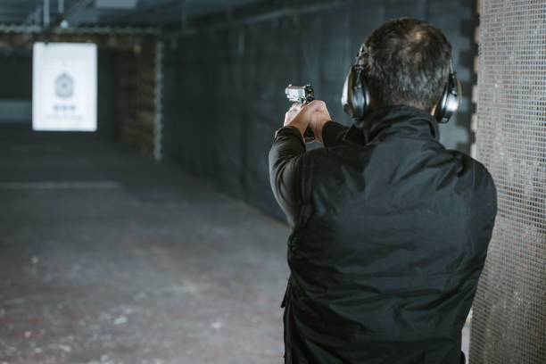 vista trasera del hombre con el objetivo de arma al blanco de tiro - target shooting gun handgun shooting fotografías e imágenes de stock