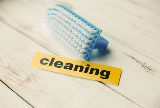 Cleaning house or office concept. Blue cleaning brush and Cleaning inscription on a white wooden background. Top view, closeup