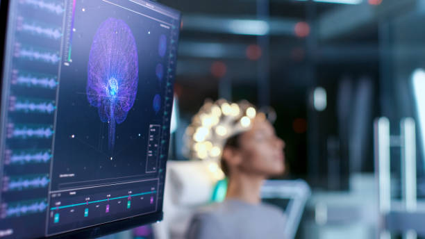 la donna che indossa cuffie per la scansione brainwave si siede su una sedia nel moderno laboratorio di studio del cervello / centro di ricerca neurologica. i monitor mostrano la lettura eeg e il modello cerebrale. - clinica di allenamento sportivo foto e immagini stock