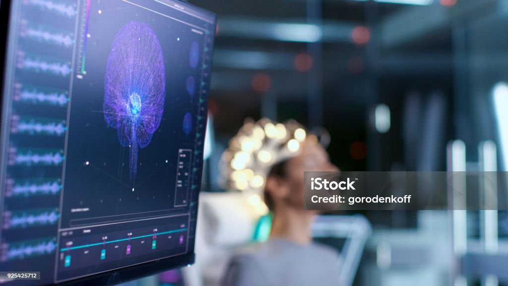 Woman Wearing Brainwave Scanning Headset Sits in a Chair In the Modern Brain Study Laboratory/ Neurological Research Center. Monitors Show EEG Reading and Brain Model. Sleeping Stock Photo