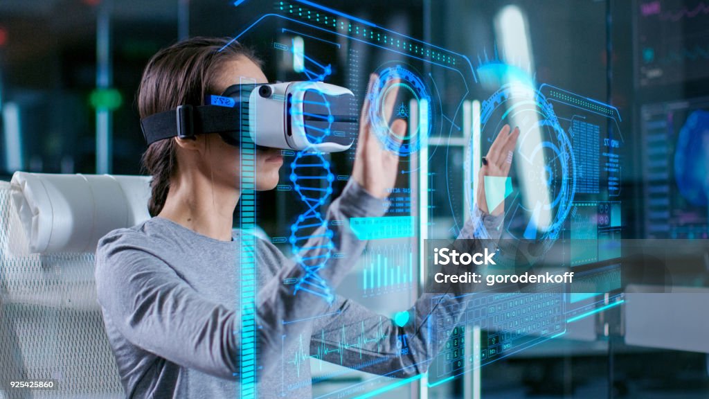 In Laboratory Scientist Wearing Virtual Reality Headset Sitting in a Chair Interacts with Futuristic Holografic Interface, Showing Neurological Data. Modern Brain Study/ Neurological Research Center. Virtual Reality Simulator Stock Photo