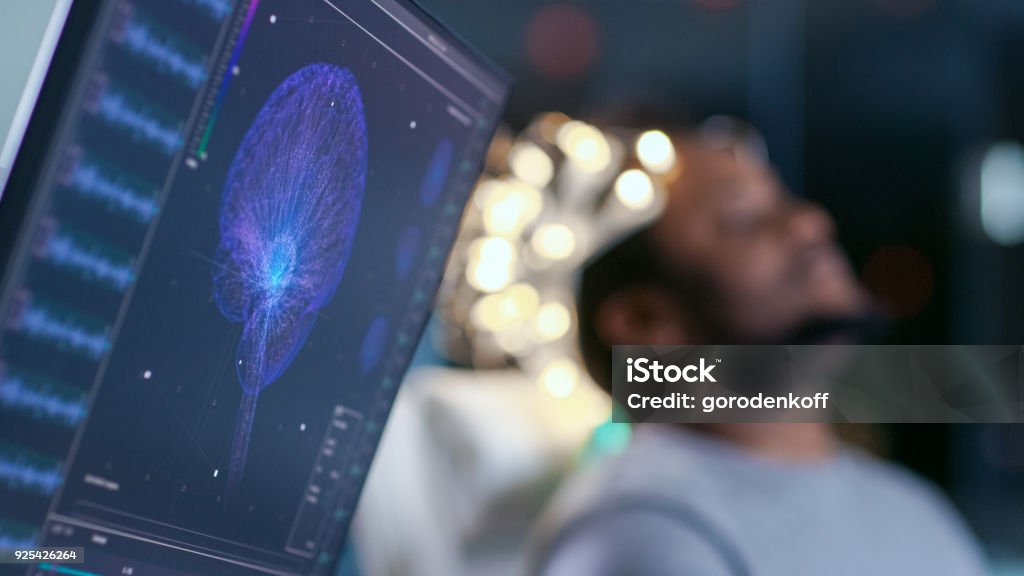 Monitors Show EEG Reading and Graphical Brain Model. In the Background Laboratory Man Wearing Brainwave Scanning Headset Sits in a Chair with Closed Eyes. In the Modern Brain Study Research Laboratory Sleeping Stock Photo
