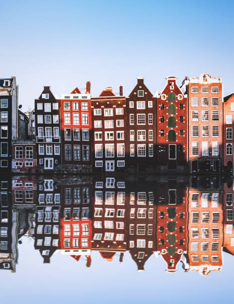 Typical Dutch Houses reflections at night on the water of the canal Amsterdam City Scene with many typical dutch houses in row and their reflection effect in the canal. Old 17th and 18th century brick houses along a canal in center of Amsterdam, Netherlands. canal photos stock pictures, royalty-free photos & images
