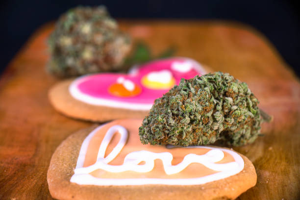 Dried cannabis nug with baked cookies on a wood tray Dried cannabis nug with baked cookies on a wood tray - infused marijuana edibles concept bud candy stock pictures, royalty-free photos & images