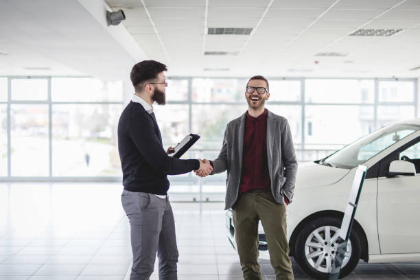 We have an agreement Young and handsome hipster man, buying a new car from the car saloon. saloon car stock pictures, royalty-free photos & images