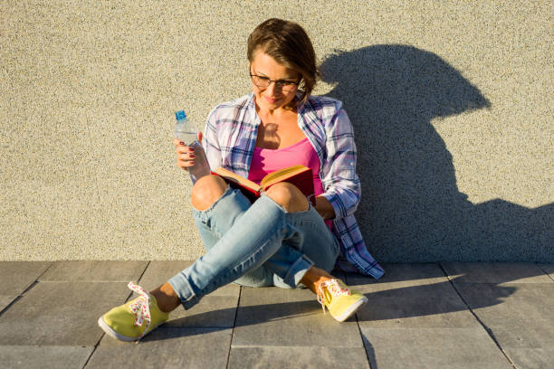 istock Smiling brunette relaxing outdoors and reading book 925436094