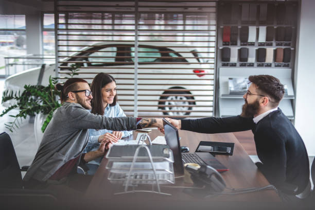 Visiting the car dealership Young and handsome hipster man, buying a new car with his girlfriend, from the car saloon. saloon car stock pictures, royalty-free photos & images