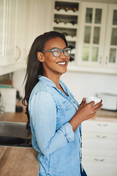 istock Smiling young African woman enjoying a coffee in her kitchen 925439564