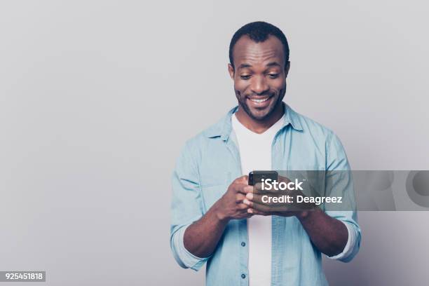 Portrait Of Handsome Excited Cheerful Joyful Delightful Curious Guy Wearing Casual Jeans Denim Shirt Sending And Getting Messages To His Lover Isolated On Gray Background Stock Photo - Download Image Now