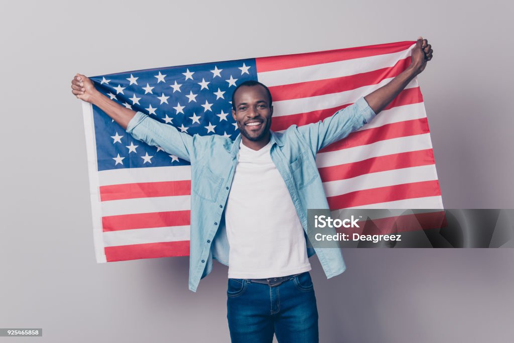 It's my native country! Portrait of cheerful glad excited confident with toothy beaming smile student wearing denim casual outfit holding flag of the USA isolated on gray background USA Stock Photo