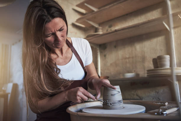 istock Artisan creatively shaping a vase turning on her pottery wheel 925465914