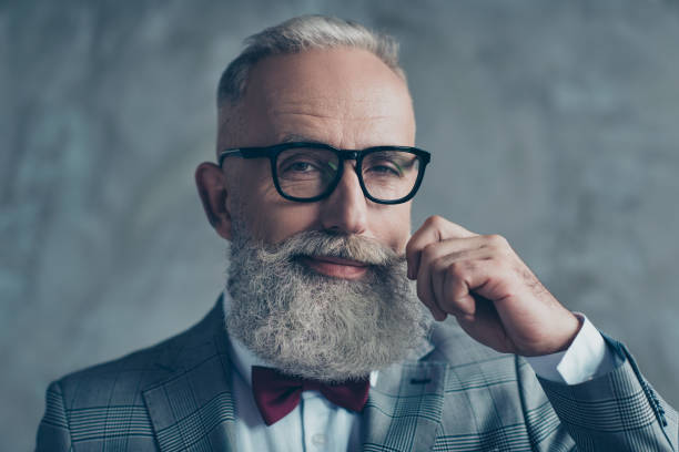 portrait du grand-père de hipster démodé branché élégant riche professionnelle affectueux pionnier grimaçant de près nette habillé avec papillon marron torsion moustache blanche isolée sur fond gris - one man only human age mustache beard photos et images de collection