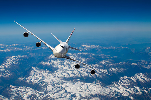 Huge four engines airplane flying over the Alps