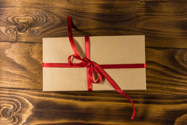 istock Cardboard gift box with red ribbon on wooden table 925470696
