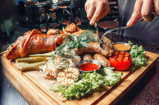 Meat on a wooden tray with roasted vegetables and sauce top view fine dining