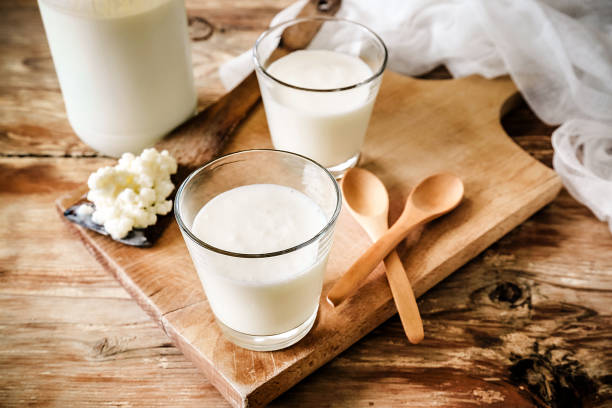 grani kefir in cucchiaio di legno con bicchiere di kefir - probiotico foto e immagini stock