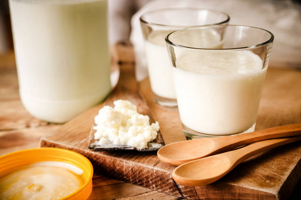 Kefir Grains In Wooden Spoon With Glass Of Kefir Organic probiotic milk kefir grains, Tibetan mushrooms, kefir grains in wooden spoon with glass of kefir. Rustic table setting, wooden table, spoon and cutting board. lactose fermentation stock pictures, royalty-free photos & images