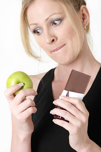 istock woman holding an apple and chocolate bar 92547450