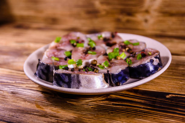 istock Sliced scomber fish with green onion on a ceramic plate on wooden table 925476228