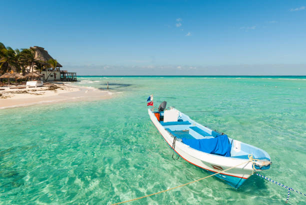 Beautiful beach with a boat, bungalow and palm trees in Isla Mujeres, Mexico.