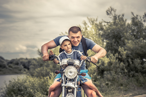 Joyful father son riding motorcycle motorbike lifestyle portrait concept happy paternity