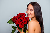 Concept of beauty purity tenderness womanhood. Close up portrait of beautiful pretty charming adorable excited with clean flawless skin woman she is smelling roses, isolated on grey background