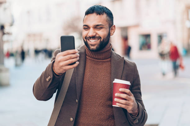 istock Smiling young man with smart phone and coffee cup 925481550