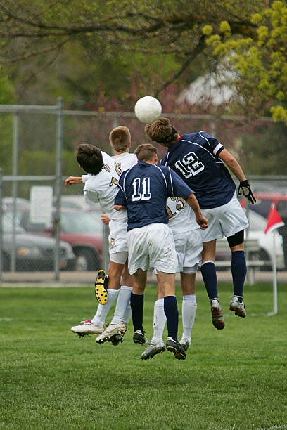 Five Young Male Soccer Players Jump to Head Ball stock photo