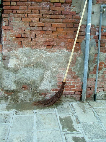 Venice Street Sweepers Broom- resting against a brick wall