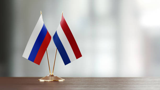 istock Russian And Dutch Flag Pair On A Desk Over Defocused Background 925492854