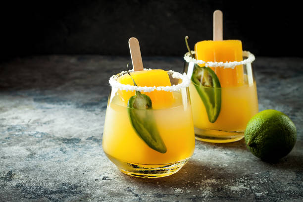 Photo of Spicy mango popsicle margarita cocktail with jalapeno and lime. Mexican alcoholic drink for Cinco de mayo party