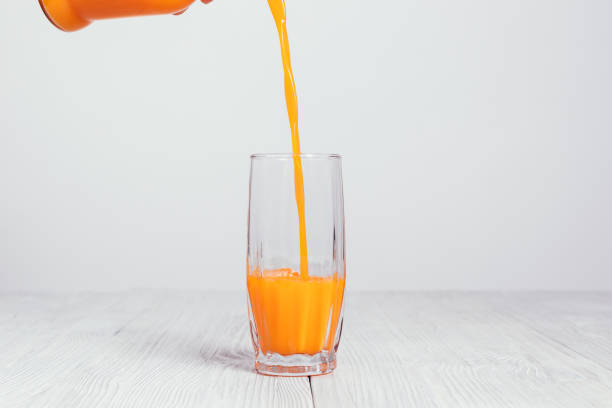istock Orange juice is poured from a bottle into a glass 925494364