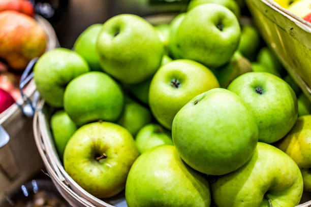 農夫の市場店のディテールとテクスチャーを示す木製バスケットに多くおばあちゃんスミス緑黄色いりんごのクローズ アップ - granny smith apple ストックフォトと画像